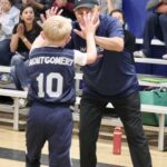 Coach high-fiving young baseball player Montgomery during a game.