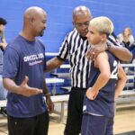 Coach giving advice to a young basketball player during a game.