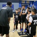 Youth basketball coach instructing young players during practice.