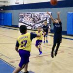 Young basketball player shooting a jump shot during a game.