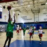 Kids playing basketball in an indoor gym.
