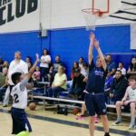 Youth basketball players compete intensely during a game in a lively gymnasium.
