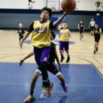 Youth basketball player jumps for a layup in a gym.