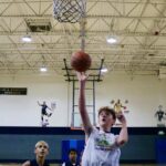A young basketball player shoots a layup during a game.