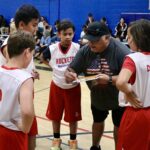 Coach discussing strategy with young basketball players during a timeout.