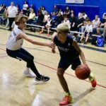 Two young boys intensely playing basketball indoors.