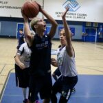 Two young boys compete intensely in a basketball game indoors.