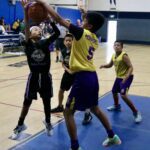 Youth basketball game with players in action near the basket.