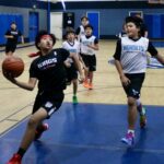 Young boys playing basketball in an indoor court.
