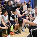 Coach instructing youth basketball players on the bench during a game.