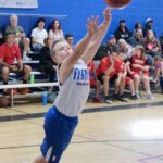 Young basketball player jumping to catch the ball in a gym.