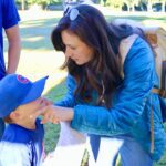 A woman affectionately touches a young boy's face outdoors.