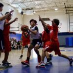 Youth basketball player drives to the hoop amid defenders.
