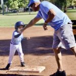 Child and adult celebrating at baseball base.