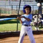 Young boy in blue baseball gear preparing to swing a bat.