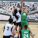 Two volleyball players jump to hit the ball during a match.
