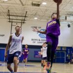 Young basketball player leaps to score during a game in a gym.