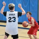 Two youth basketball players competing, one defending and one preparing to shoot.