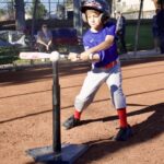 Young boy practicing tee-ball swing on a sunny day.