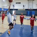 A young boy attempts a basketball shot during a game in a gymnasium.