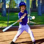 Young baseball player swinging at a pitch on a sunny day.