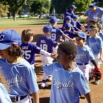 Children in blue Royals baseball uniforms shaking hands after a game.