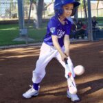 Young baseball player swinging at a pitch during a game.