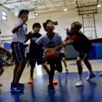 Kids playing basketball intensely in a gym.