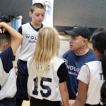 Coach instructing young basketball players during practice.