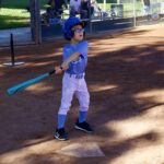 A young boy in baseball gear ready to bat on a sunny day.