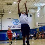 Young basketball player jumping for a shot in a gymnasium.