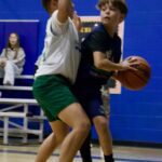 Two boys competing in a basketball game indoors.