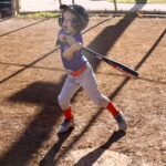 Young child swinging a baseball bat on a sunny day.