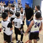 Youth basketball team huddling with coach during a game.
