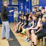 Coach instructing young basketball team during practice.