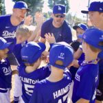 Youth baseball team in Dodgers uniforms doing a group cheer.
