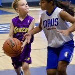 Young girls playing basketball in a gym.