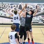 Two basketball players jump for the ball during a tip-off at the start of the game.