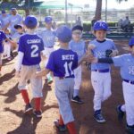 Youth baseball players exchanging high-fives before a game.