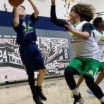 Two boys competing in a basketball game indoors.