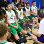 A youth basketball team listens to their coach during a timeout.