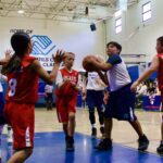 Kids playing basketball indoors on a court.