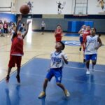 Kids playing basketball in a gym during a game.