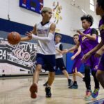 Young boys playing basketball indoors, one dribbling the ball.