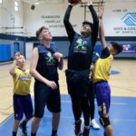 Youth basketball players compete for a rebound during a game in a gym.