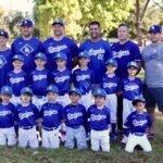 Youth baseball team posing outdoors in Dodgers uniforms.