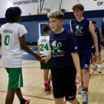 Young basketball players shake hands after a game in a gymnasium.