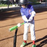 Child preparing to hit a baseball off a tee at a park.