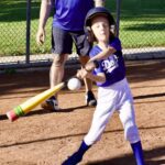 Young baseball player swings at a pitch during a game.