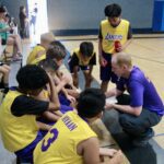 Basketball coach giving strategy to young players during timeout.